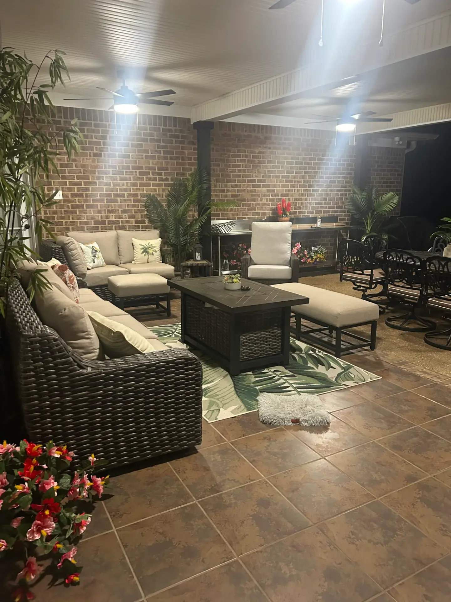 Covered patio with wicker seating, brick walls, and ceiling fans